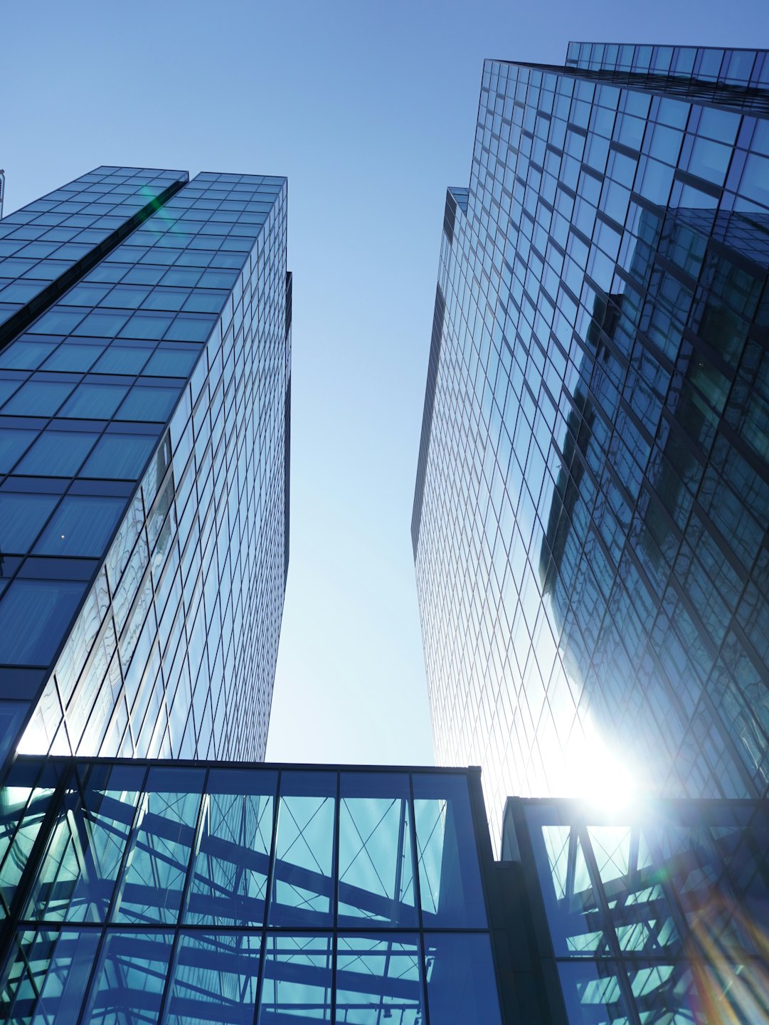 Two modern glass office buildings connected by a skywalk.
